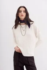Remera color crudo de calce relajado y manga larga, con detalle de encaje en espalda y hombros.