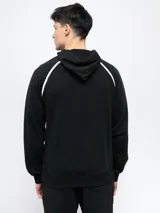 Canguro de felpa color crema con capucha, cordones y logo Umbro bordado en rojo. Presenta ribete rojo en hombros y bolsillo tipo canguro con cierre lateral.