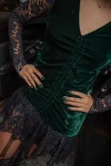 Vestido corto negro de terciopelo con escote en V, mangas largas de encaje y falda con volantes de encaje.