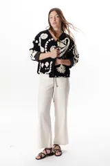 Chaqueta color crudo con bordados florales en tonos rojo, verde y negro.