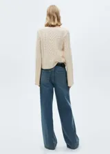 Sweater color crema de tejido de punto trenzado, con cuello redondo y mangas acampanadas.