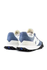 Championes urbanos New Balance de gamuza azul con detalles en gris y blanco. Presentan el logo 'N' en el lateral, cordones blancos y suela de goma negra con detalles en blanco.