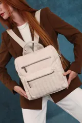 Mochila mediana de símil cuero color beige, con asa superior, dos compartimentos principales con cierre y dos bolsillos frontales con cierre. Las correas son ajustables y de color beige.
