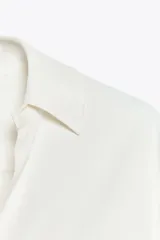 Camisa de mujer satinada color blanco, confeccionada en hilatura con viscosa. Tiene cuello solapa, manga larga con puños y cierre frontal con botones.