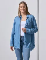 Camisa de jean celeste con flecos en el ruedo, de mangas largas y corte recto.