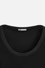 Musculosa negra ajustada al cuerpo, con cuello redondo y sisas amplias.