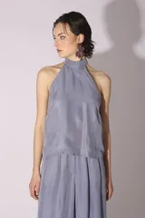 Conjunto de blusa y pantalón color gris azulado de seda, con cuello halter y corte holgado.