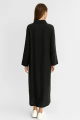 Túnica color beige de lino, de corte holgado, con cuello camisero, cierre frontal con botones, manga larga y bolsillo en el pecho.