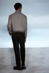Pantalón negro de corte relajado, con cintura elástica ajustable con cordón, cierre con botón y corchete, bolsillos laterales y traseros.