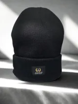 Gorro de lana negro con etiqueta de la marca Alquimia en el dobladillo.