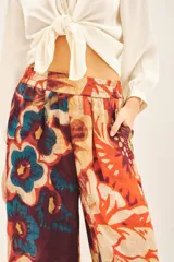 Pantalón capri con estampado floral en tonos naranja, rojo, azul y marrón. Tiene corte regular, bolsillos laterales y elástico en la parte trasera de la cintura.