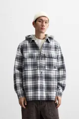 Sobrecamisa relaxed fit de algodón a cuadros azul marino y blanco, con capucha gris combinada a contraste, manga larga con puños abotonados, bolsillos plastrón en el pecho, bolsillos laterales en la cadera y cierre frontal con botones.