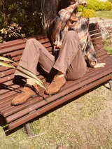 Botas cortas de gamuza color marrón, con cierre lateral y detalle de hebilla metálica.