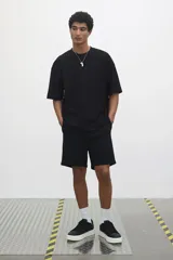 Remera negra de punto de algodón pesado, corte oversized, con cuello redondo ribeteado, hombros caídos y bajo recto.