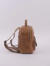 Mochila de cuero color marrón claro, con múltiples bolsillos externos con cierre y aplique trasero para colocar en carry on.