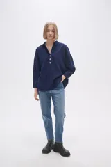 Blusa blanca holgada de poliéster con cuello camisero y mangas largas.