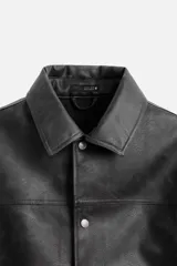 Cazadora cropped fit confeccionada en tejido efecto piel color negro. Tiene cuello solapa, manga larga con puño abotonado, bolsillos de vivo en cadera, bolsillo interior y cierre frontal con botones a presión.