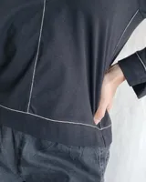 Remera blanca de mangas largas con cuello en V y costuras a la vista.
