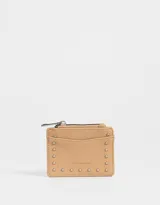 Monedero color beige de cuero sintético con cierre superior y apliques de tachas en forma de estrella.