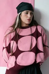 Buzo de tejido de punto color crema con grandes círculos negros estampados. Tiene cuello redondo, puños y bajo acanalados.