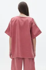 Remera de denim color rosa con efecto lavado, corte oversized, cuello redondo en contraste color crema, mangas cortas con rayas laterales y bordados en el frente.