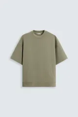 Sudadera verde oliva de corte holgado, confeccionada en tejido interlock de algodón con elasticidad. Tiene cuello redondo, mangas cortas y bajo con terminación en rib.