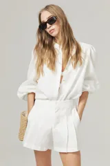 Camisa blanca de lino con cuello mao, mangas largas abullonadas con puño elástico y corte holgado.