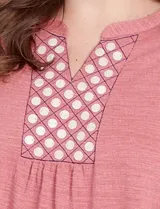 Blusa de manga tres cuartos color rosado, confeccionada en modal texturizado. Presenta un escote en V con cuello a la base y apliques nacarados en el área del escote.