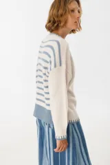 Sweater de punto color crudo con cuello redondo y terminaciones en celeste.
