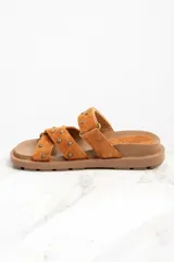 Sandalias marrones de gamuza con apliques de tachas doradas, con dos tiras anchas sobre el empeine y suela plana.