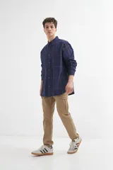 Camisa azul a cuadros grises de manga larga con cuello abotonado y bolsillo en el pecho.