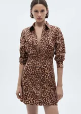 Vestido corto camisero con estampado de leopardo en tonos marrones y beige. Tiene cuello camisero, cierre frontal con botones, mangas largas abotonadas y corte recto.
