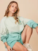 Sweater color crema con degradé a naranja, con cuello redondo y logo estampado de palmera en el pecho.