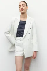 Blazer blanco de tweed, con corte recto y seis botones metalizados al frente.