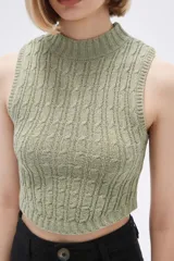Chaleco verde pálido de punto con cuello alto y diseño trenzado.