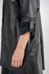 Chaqueta negra de cuero ovino con corte recto y lazo de ajuste en la cintura.