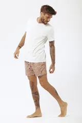 Short de baño estampado con motivos de hojas tropicales en tonos verde, beige y naranja.