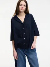 Camisa color gris claro de mangas 3/4 con botones en la parte delantera. Corte holgado.