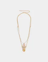 Collar corto multicadena dorada, con una cadena de eslabones y otra de perlas. Incluye dijes de zapatos de ballet rosados, moño y flor de metal dorados.