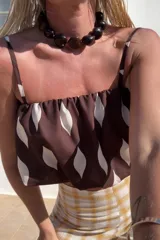 Top corto marrón con estampado de hojas blancas, breteles finos y corte recto.