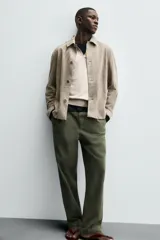 Cazadora de hombre de corte regular fit, confeccionada en piel con acabado ante color beige claro. Presenta cuello solapa, manga larga con puño de botón, bolsillos de plastrón en la cadera y cierre frontal con botonadura.