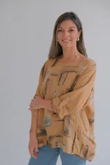 Blusa color ocre con estampado abstracto en tonos marrones y grises. Tiene cuello redondo y mangas 3/4 con botón.