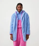 Bata de baño en tejido sherpa color celeste con capucha, cierre delantero y mangas largas. Presenta bies contrastante en color rosa.