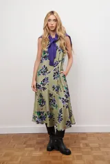 Vestido midi color beige con estampado de hojas en tonos violeta, verde y negro. Diseño sin mangas, con escote redondo y falda acampanada.