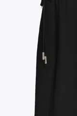Pantalón negro de tiro alto con cintura elástica ajustable con cordones laterales, forro interior corto y pernera ancha.