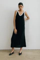 Vestido midi negro con escote en V, breteles finos con volados blancos y tajos laterales.