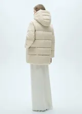 Campera puffer larga color beige, con capucha, cierre frontal con cremallera y bolsillos laterales con cierre.