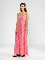 Vestido largo hasta el tobillo de viscosa y poliamida, con estampado de rayas verticales rosas y flores rojas. Tiene breteles finos, escote en V profundo y detalle de flor Polonio en cobre.