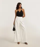 Pantalón pantalona de corte sastrero color blanco, confeccionado en poliéster y elastano, con cintura ancha con trabillas y pliegues delanteros.