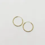 Aros tipo argolla de plata 925 con baño de oro, presentando una textura facetada o labrada en toda su superficie.